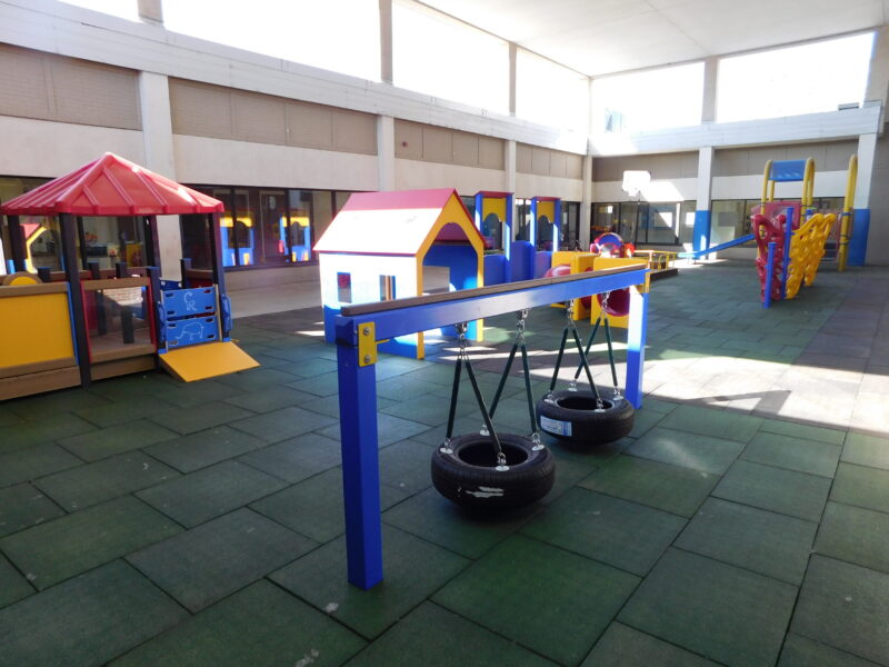 Small tires wings and playhouses in an enclosed padded playground. 
