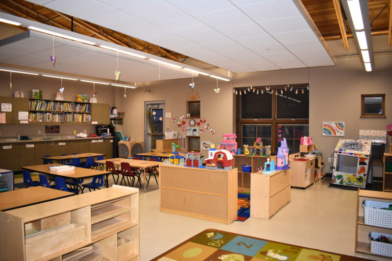 Preschool classroom with shelves, tables, chairs, and toys.