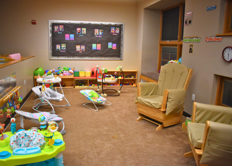 Infant room with rocking chairs, baby toys, and bouncers.